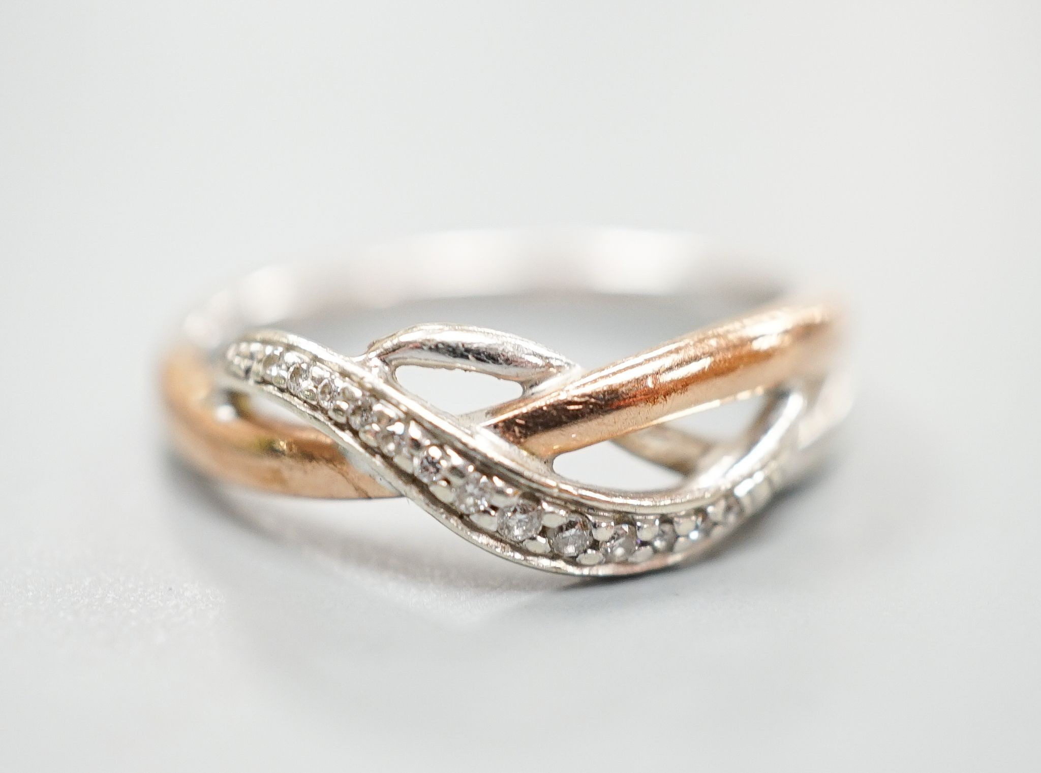 A modern two colour 9ct gold and diamond chip set crossover ring, size Q, gross weight 3.8 grams.